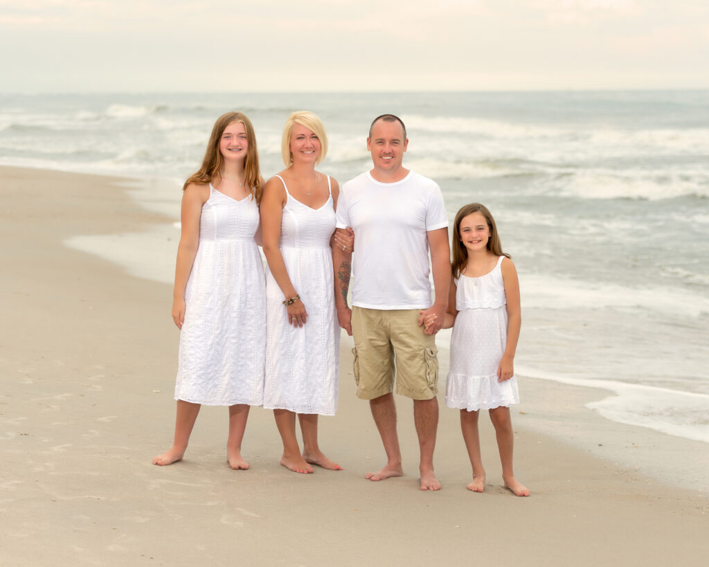 Best Family Beach Photographer image from Surf City NC of a Family Posing Next To The Ocean Dressed In White